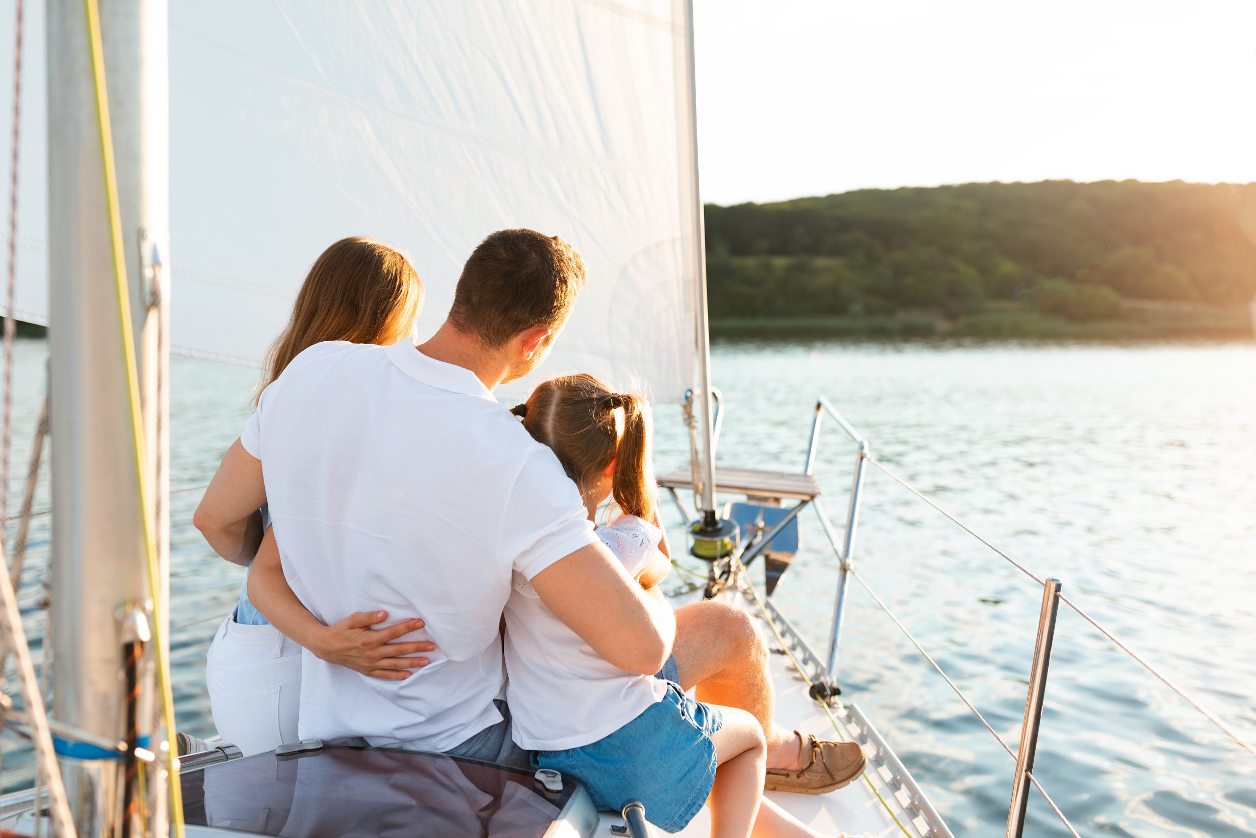 Family Enjoying Yacht Tour Sitting On Deck Sailing In Sea
